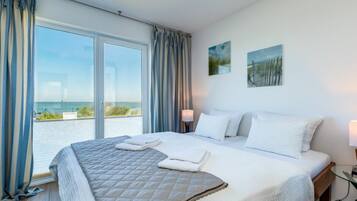 A hotel room with a large bed, a view of the sea, and a balcony.