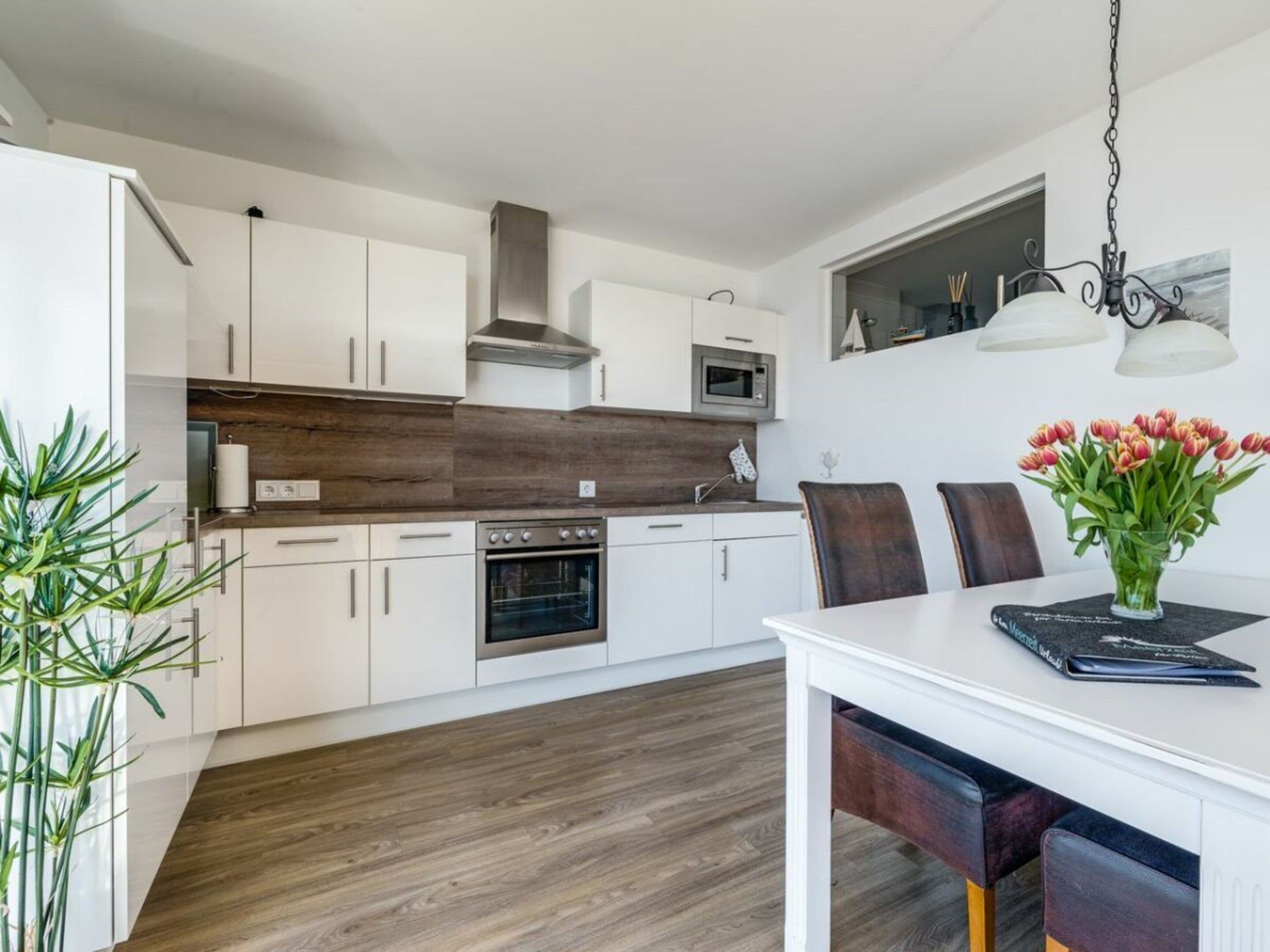 A modern kitchen with white cabinets, a wooden countertop, and a dining area with a table and chairs.