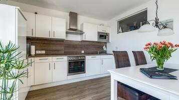 A modern kitchen with white cabinets, a wooden countertop, and a dining area with a table and chairs.