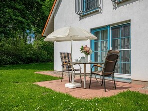 An outdoor patio with a table and chairs, a white umbrella, and a vase of flowers. - 11/t6 Holiday Home Park \"freesenbruch\" (Zingst)