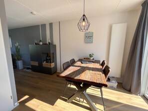 A dining area with a wooden table, chairs, and a hanging light fixture.