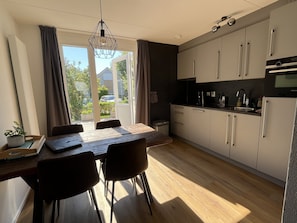A modern kitchen with a dining area, large windows, and a view of the outdoors. - Modern vacation home with a garden (fenced on the west side) and a private dock on the IJsselmeer (Makkum)