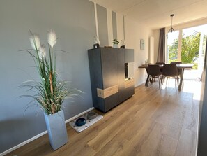 A modern living room with a dining area, a large potted plant, and a pet feeding station. - Modern vacation home with a garden (fenced on the west side) and a private dock on the IJsselmeer (Makkum)