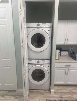 A laundry room with two stacked front-loading washing machines. - Island Retreat with Private Beach, River Views, Great Restaurants & Live Music (Jensen Beach)