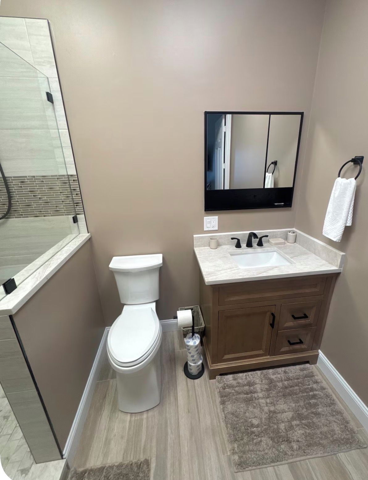 A modern bathroom with a toilet, sink, and mirror.