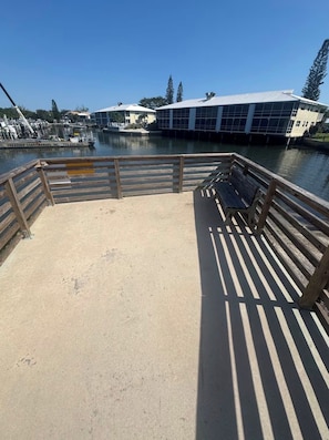 A waterfront promenade with a wooden deck, benches, and a marina in the background. - Island Retreat with Private Beach, River Views, Great Restaurants & Live Music (Jensen Beach)