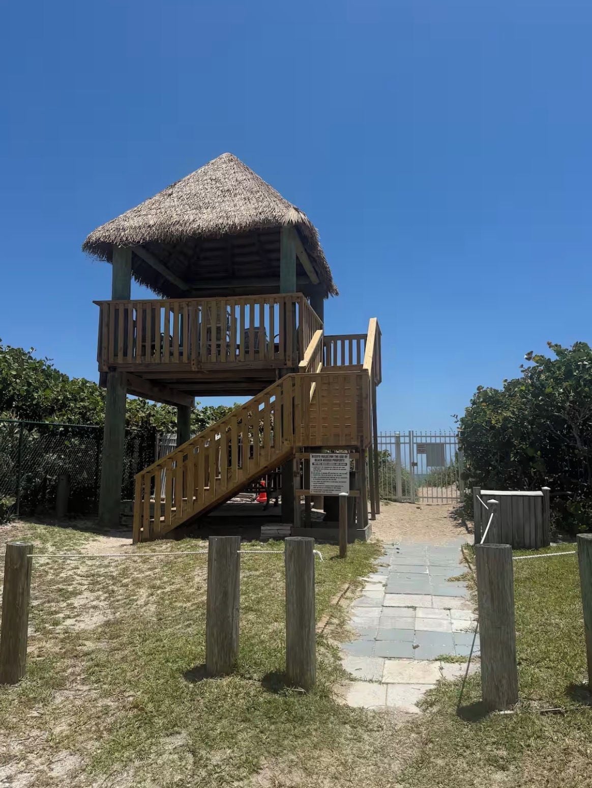 A wooden structure with a thatched roof and a wooden staircase leading to a deck.