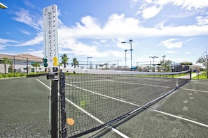 A tennis court with a net, surrounded by a fence, and a sign indicating the court's surface type. - Michigander's Dream (Punta Gorda)