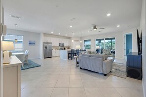 A modern kitchen with white cabinets, a refrigerator, and a dining area with a table and chairs. - Michigander's Dream (Punta Gorda)