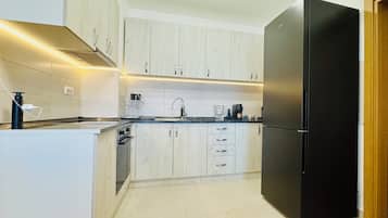 A modern kitchen with white cabinets, a black refrigerator, and a built-in oven.