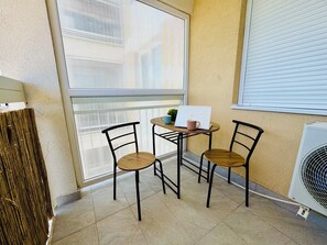 A small balcony with two chairs, a table, and a laptop.