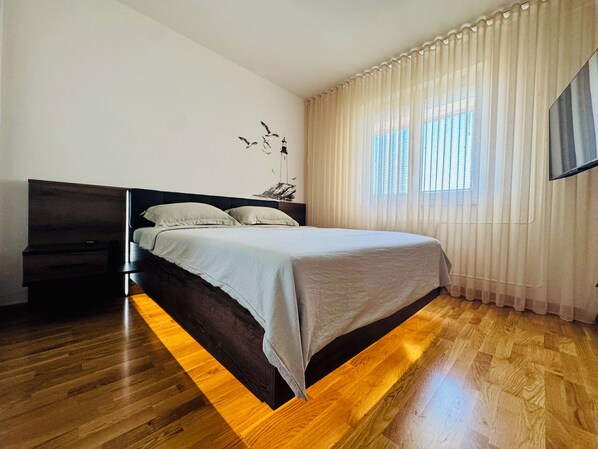 A bedroom with a bed, a nightstand, and a wall-mounted TV.