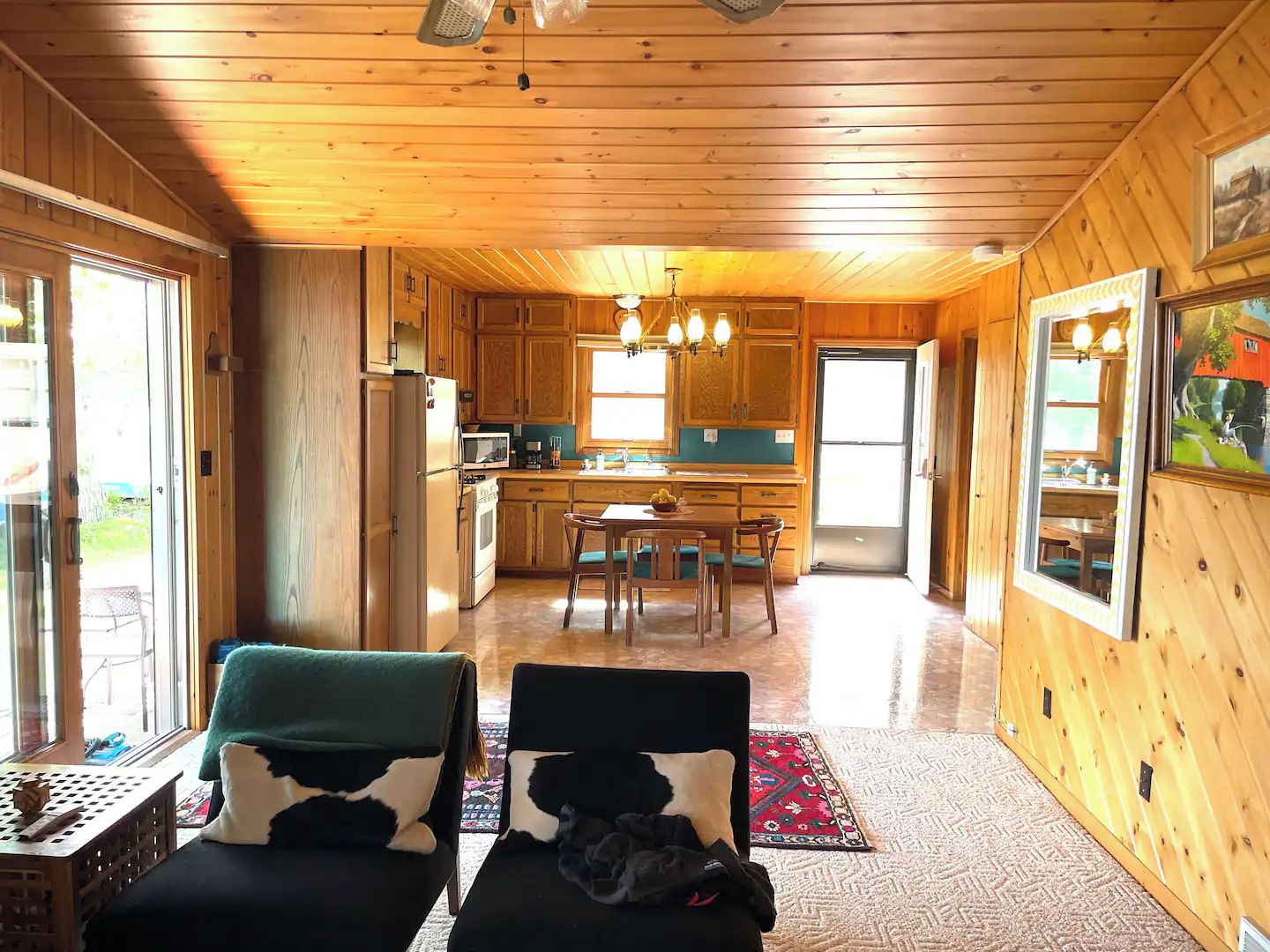 Un intérieur en bois comprenant une cuisine, un coin repas et deux fauteuils.