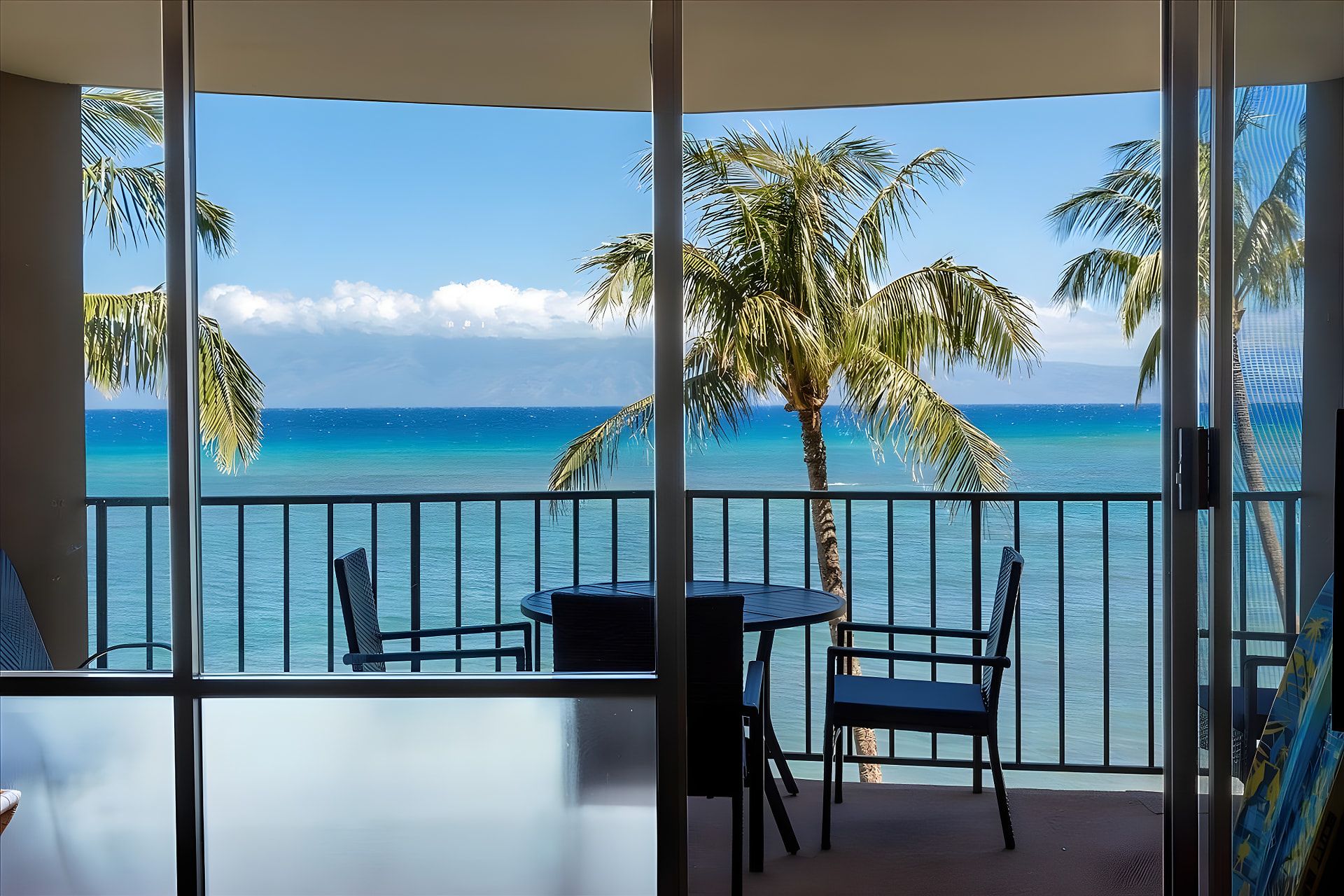 A balcony with a view of the ocean and palm trees.