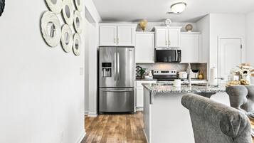 A modern kitchen with white cabinetry, stainless steel appliances, and a granite countertop.