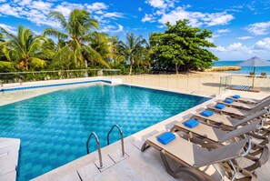 A clear blue pool with lounge chairs and a palm tree backdrop. - CASA PRIVADA 4 - AREIA BARU (Bolívar)