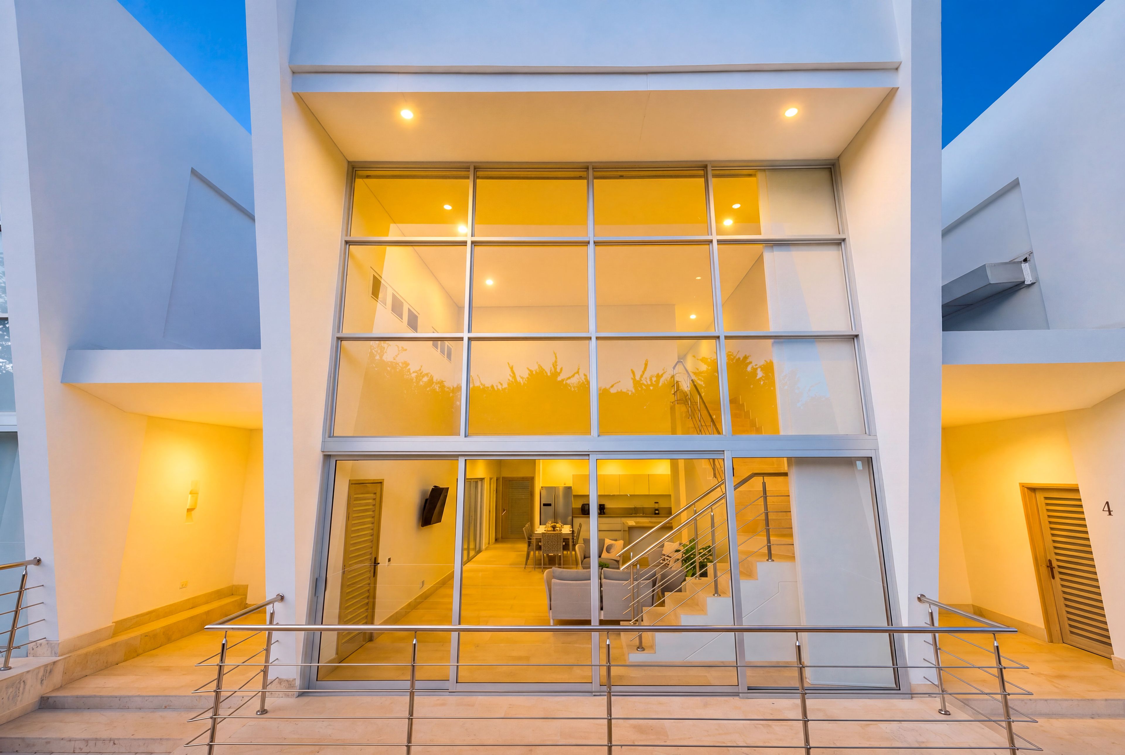 Un edificio moderno con fachada de vidrio, una escalera que lleva a un nivel superior y un área de cocina visible.