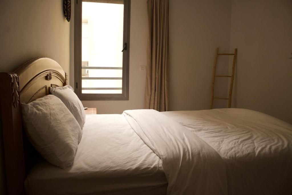 A single bed with a wooden headboard, a bedside table, and a window with curtains.