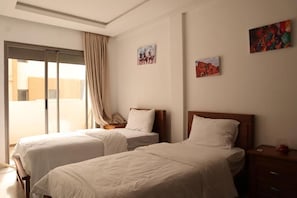 Ein Hotelzimmer mit zwei Betten, einer Schiebetür zu einem Balkon und Bildern an den Wänden.
