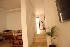 Una sala de estar con un sofá, una mesa de centro y una escalera que lleva a otra habitación.