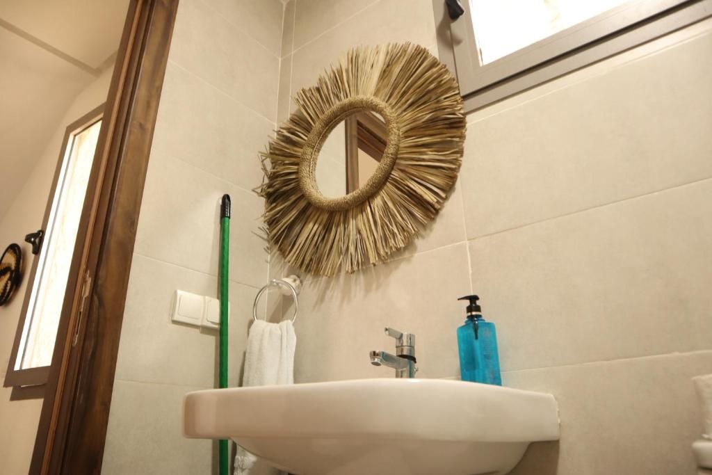 A bathroom with a sink, mirror, and a decorative wall piece.