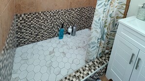 Un baño con ducha, ventana y lavabo con artículos de aseo.