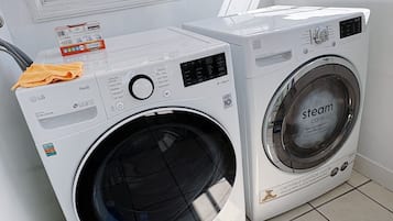 Un espace buanderie comprenant deux machines à laver, une bouteille de lessive et un chiffon de nettoyage.