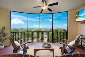 A balcony with a view of a residential area, a ceiling fan, and wooden furniture.
