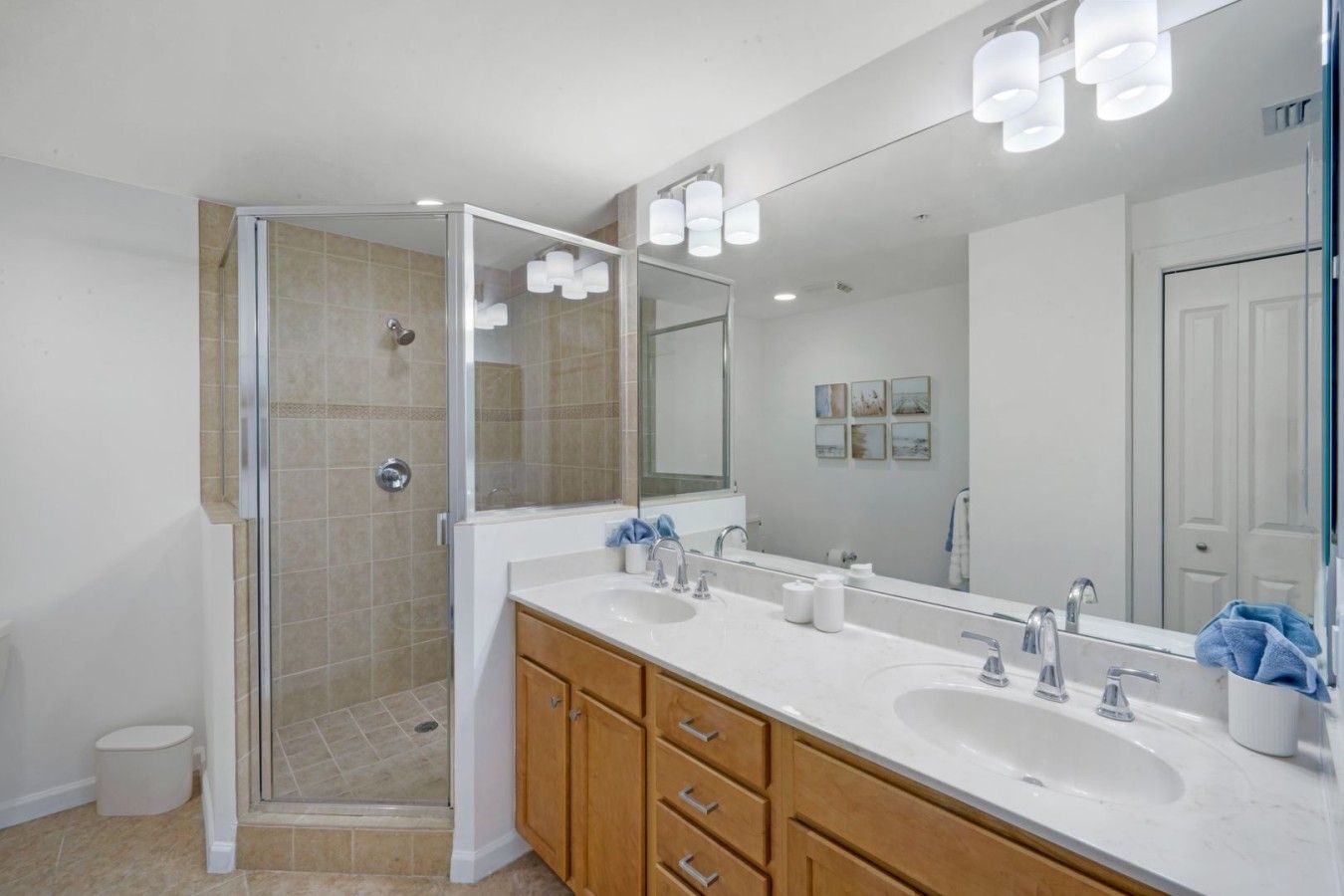 A modern bathroom with a glass-enclosed shower, a double sink vanity, and a large mirror.