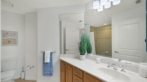 Ein modernes Badezimmer mit Toilette, Waschbecken mit Spiegel und blauem Handtuch an der Wand.