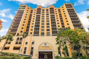 Um hotel de vários andares com entrada imponente, varandas e céu claro.