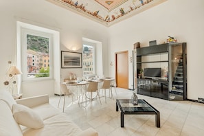 Un soggiorno moderno con zona pranzo, un divano, un tavolino e una TV su un mobile nero.