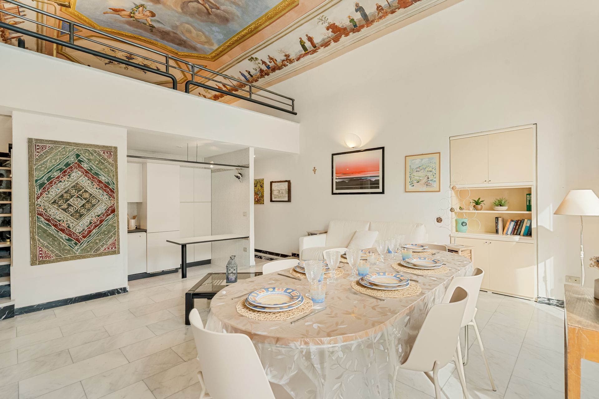 A spacious dining area with a high ceiling and a view of the upper floor.