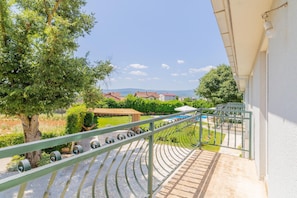 A balcony with a view of a swimming pool, a tree, and houses in the background. - Hilly Stone Villa for 10 Guests in Donji Vinjani (Donji Vinjani)
