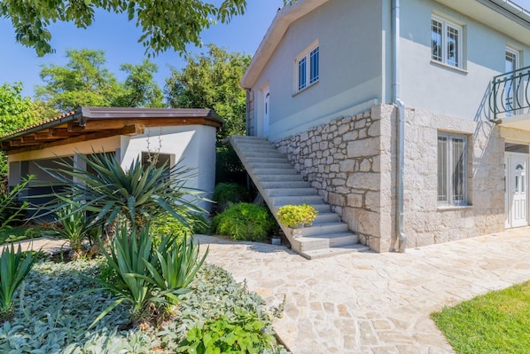 A two-story house with a stone staircase leading to the upper floor.