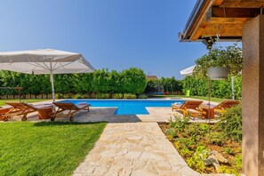 A swimming pool with lounge chairs and umbrellas, surrounded by a garden and a stone pathway. - Hilly Stone Villa for 10 Guests in Donji Vinjani (Donji Vinjani)