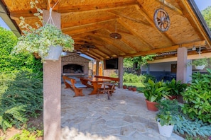 An outdoor patio with stone flooring, wooden furniture, and hanging plants. - Hilly Stone Villa for 10 Guests in Donji Vinjani (Donji Vinjani)