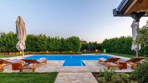 A swimming pool with lounge chairs and a covered umbrella.