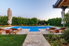 A swimming pool with lounge chairs and a covered umbrella.