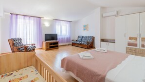A bedroom with a bed, a TV, a sofa, and a wardrobe.