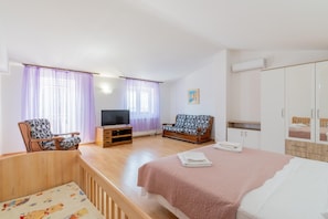 A bedroom with a bed, a TV, a sofa, and a wardrobe.