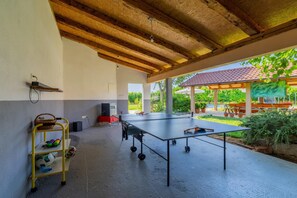 An outdoor covered area with a ping pong table, a speaker, and a metal rack with sports equipment. - Hilly Stone Villa for 10 Guests in Donji Vinjani (Donji Vinjani)