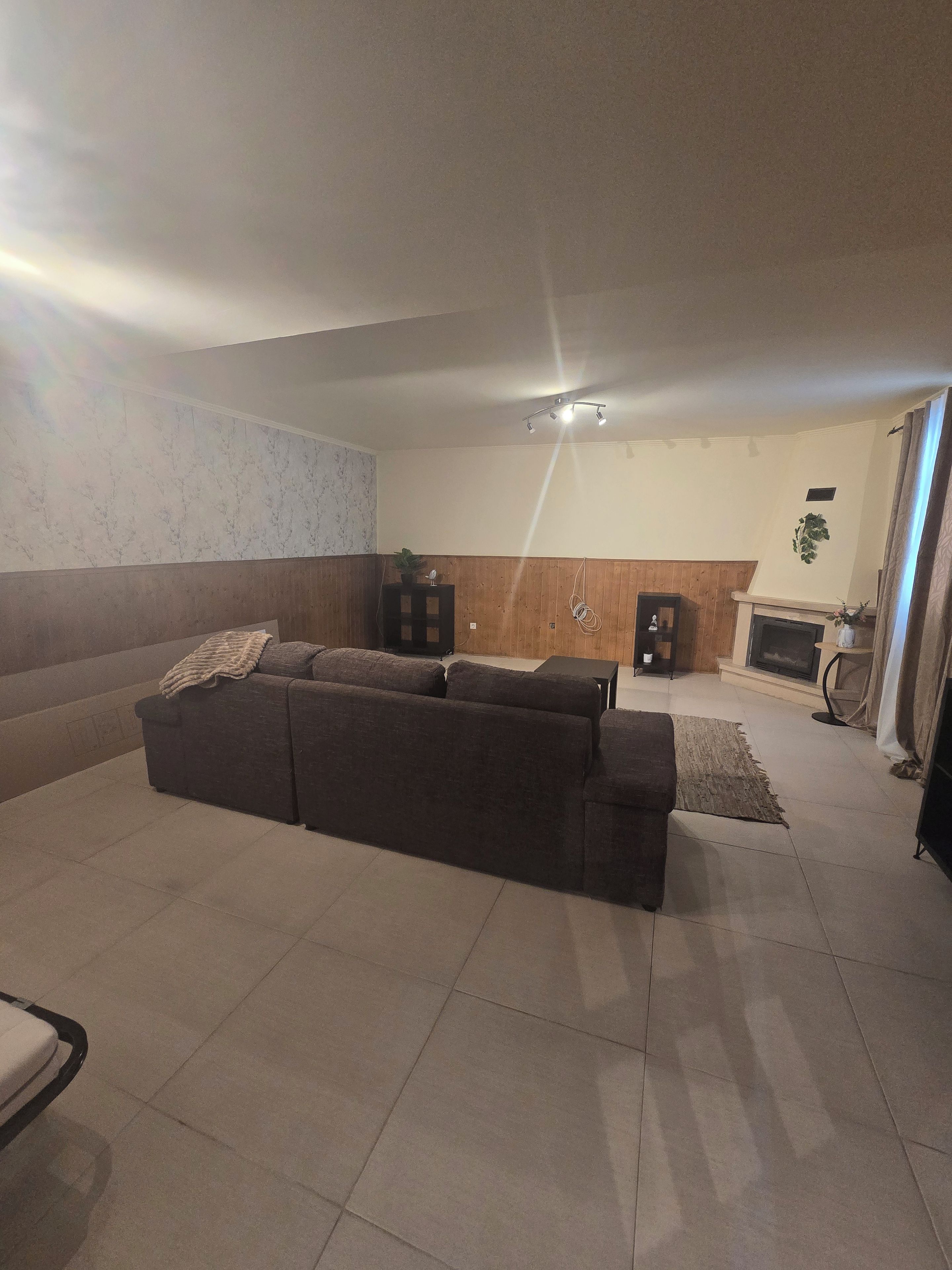 Un salon avec un canapé, une cheminée et un luminaire au plafond.