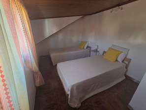 A room with two beds, a small table, and a curtain.