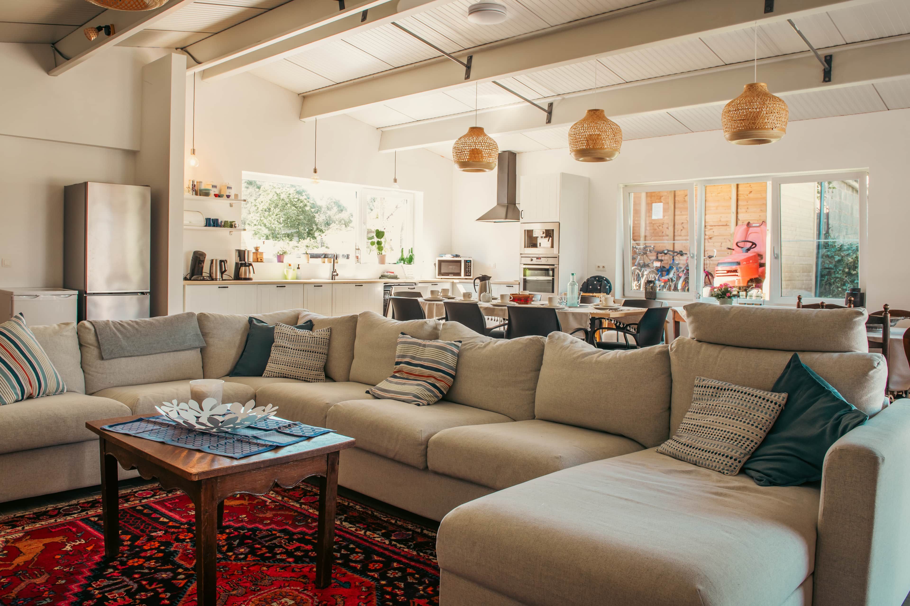 A spacious living area with a sofa, coffee table, and a view of the kitchen and dining area.