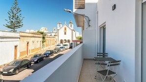 Ein schmaler Balkon mit Blick auf parkende Autos und ein Gebäude mit einem Glockenturm.