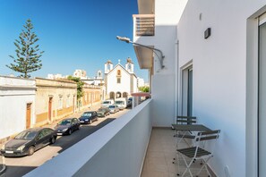 A narrow balcony with a view of parked cars and a building with a bell tower. - Privilege 3-Bedroom Casa dos Capuchinhos in the heart of Faro (Faro)