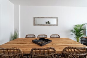 A wooden dining table with six wicker chairs, a black tray, and a mirror on the wall. - Privilege 3-Bedroom Casa dos Capuchinhos in the heart of Faro (Faro)
