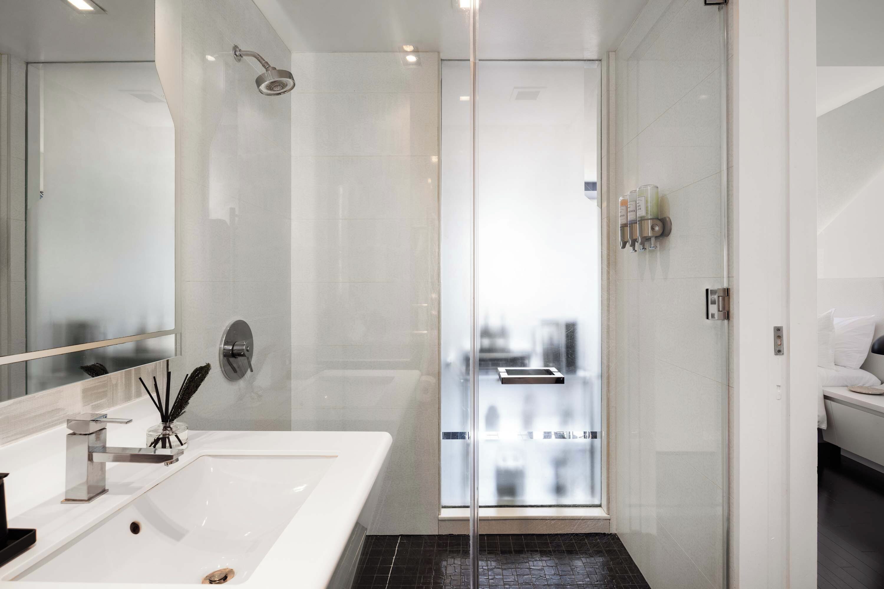 A modern bathroom with a large mirror, a shower, and a sink.