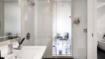 A modern bathroom with a large mirror, a shower, and a sink.